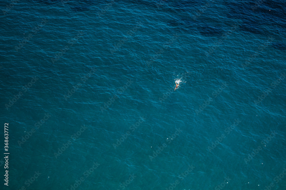 A man is swimming in the clear water of the Costiera Amalfitana