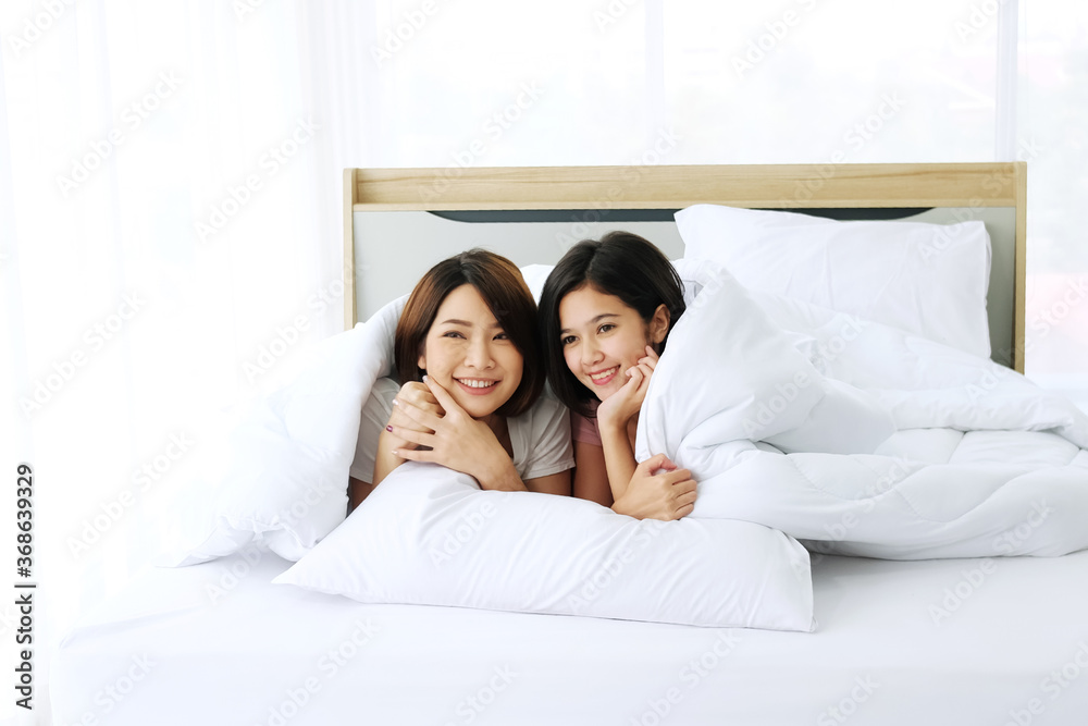 Asian young sisters lovely couple relaxing and smiling together when wake up in bedroom. Family on Holiday and Homosexual women or Lesbian lifestyle concept.