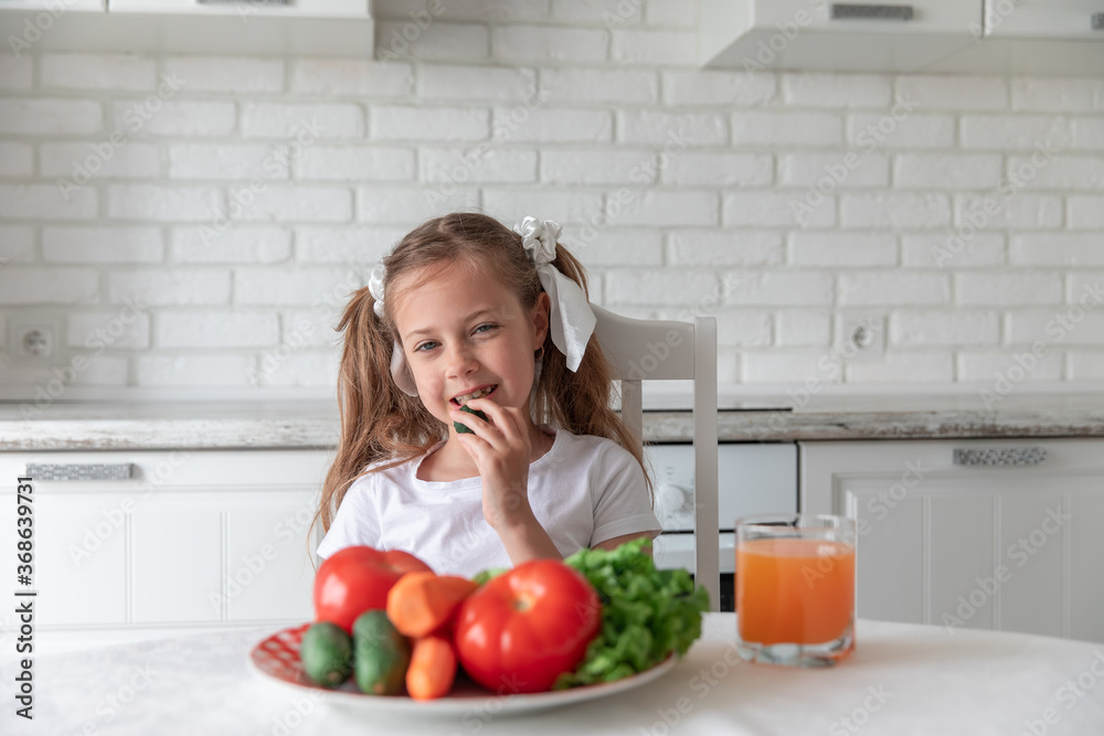 little girl eats vegetables in the kitchen. healthy food. little girl eats vegetables in the kitchen. healthy food.