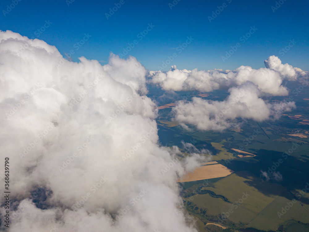 High flight in the clouds over agricultural fields in summer.