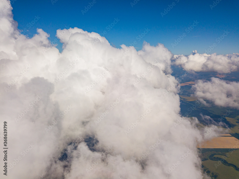 High flight in the clouds over agricultural fields in summer.