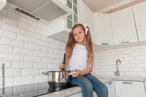 beautiful little girl with a pan and the ladle
