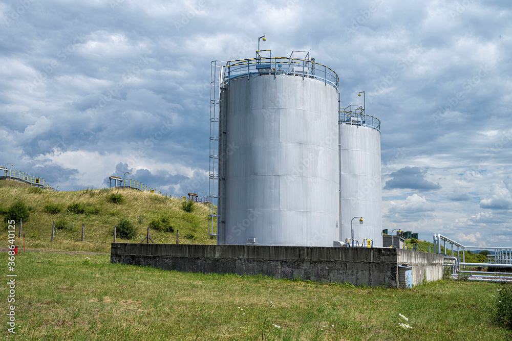 Two petrochemical tanks on the fuel base with underground tanks on the background, Europe Two petrochemical tanks on the fuel base with underground tanks on the background, Europe