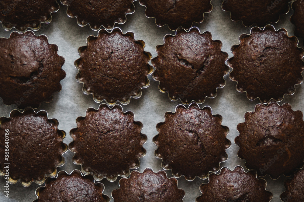 Fresh baked chocolate muffins standing in a form with paper. Top view. Fresh baked chocolate muffins standing in a form with paper. Top view.