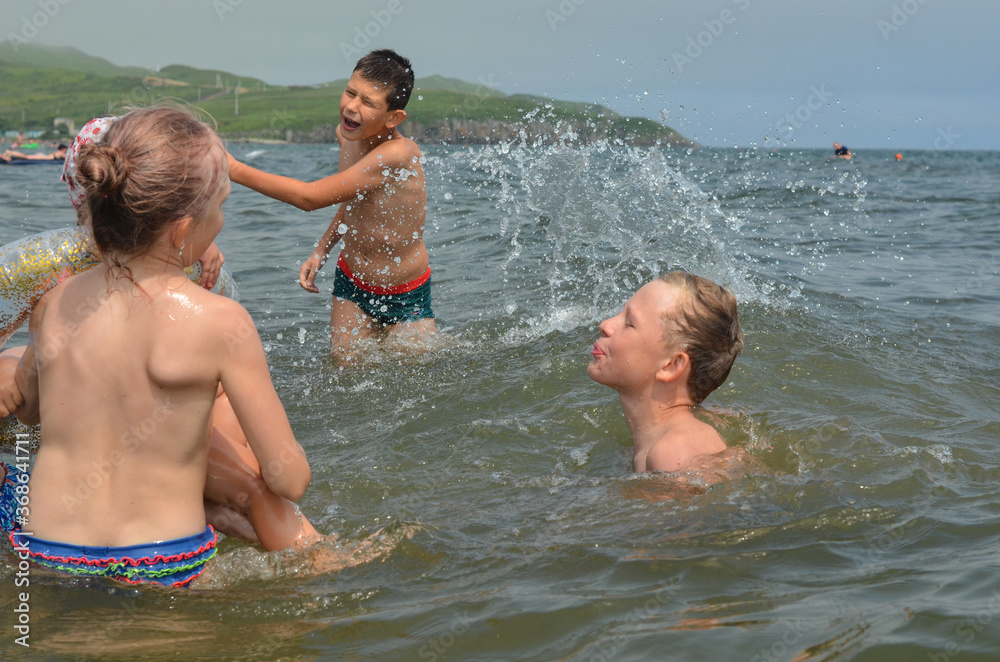Caucasian children in the sea on the beach in summer Caucasian children in the sea on the beach in summer