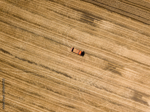 Aerial drone view. Truck with grain in a ripe wheat field in Ukraine.