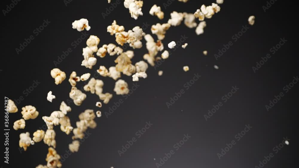 Bunch of crunchy popcorn flying up in air and falling down in slow motion on gray background Bunch of crunchy popcorn flying up in air and falling down in slow motion on gray background