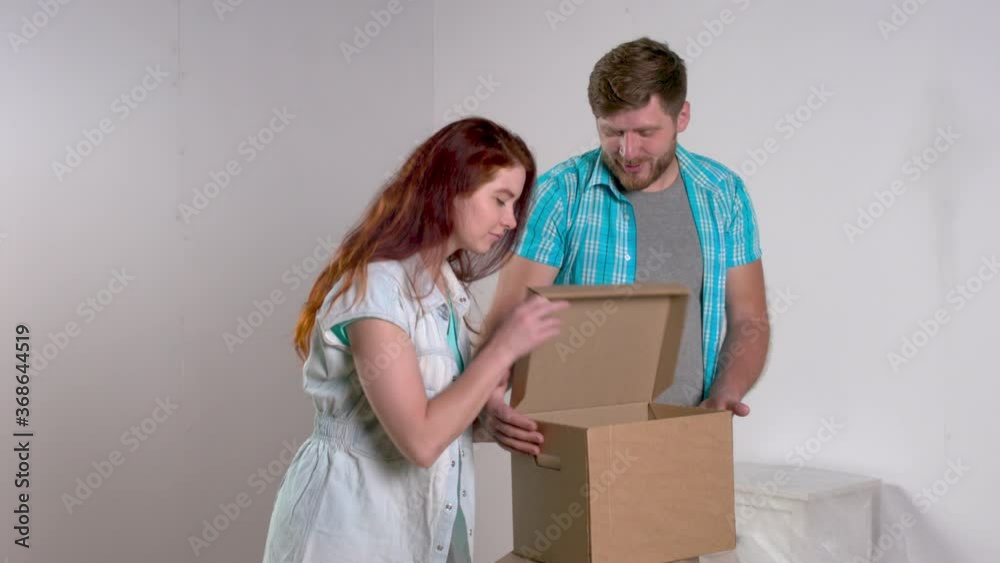 Young couple dismantles boxes of belongings while moving to new apartment. Lifestyle concept Young couple dismantles boxes of belongings while moving to new apartment. Lifestyle concept