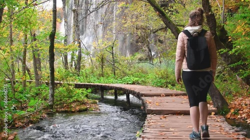 Autumn Plitvice Lakes, National Park in Croatia, UNESCO world heritage. Woman trekking on wooden trail