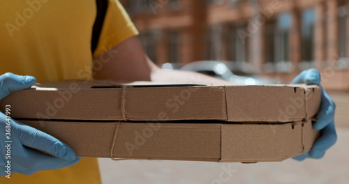 A man holds two flat boxes in his hands, standing in the middle of a residential complex.