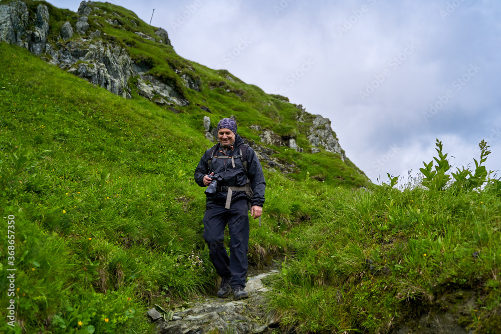 Fototapeta premium Hiker man with backpack on a mountain trail