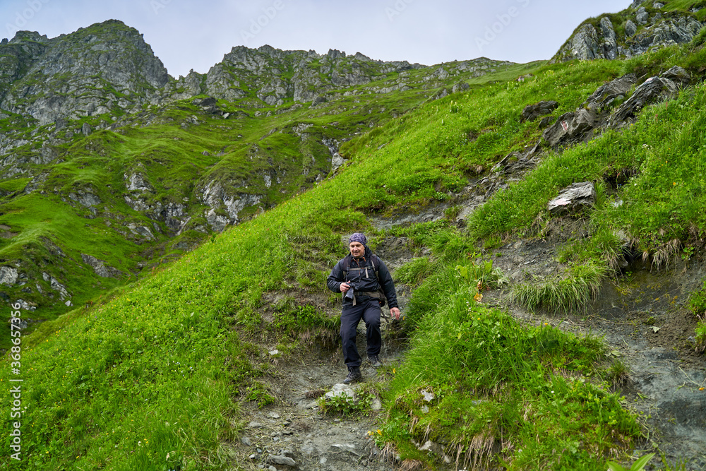 Hiker man with backpack on a mountain trail