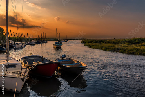 Boats moored on the River Glaven at Blakeney, Norfolk, UK at sunset photo