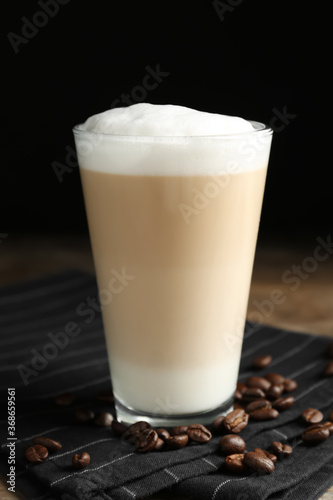 Delicious latte macchiato and coffee beans on napkin