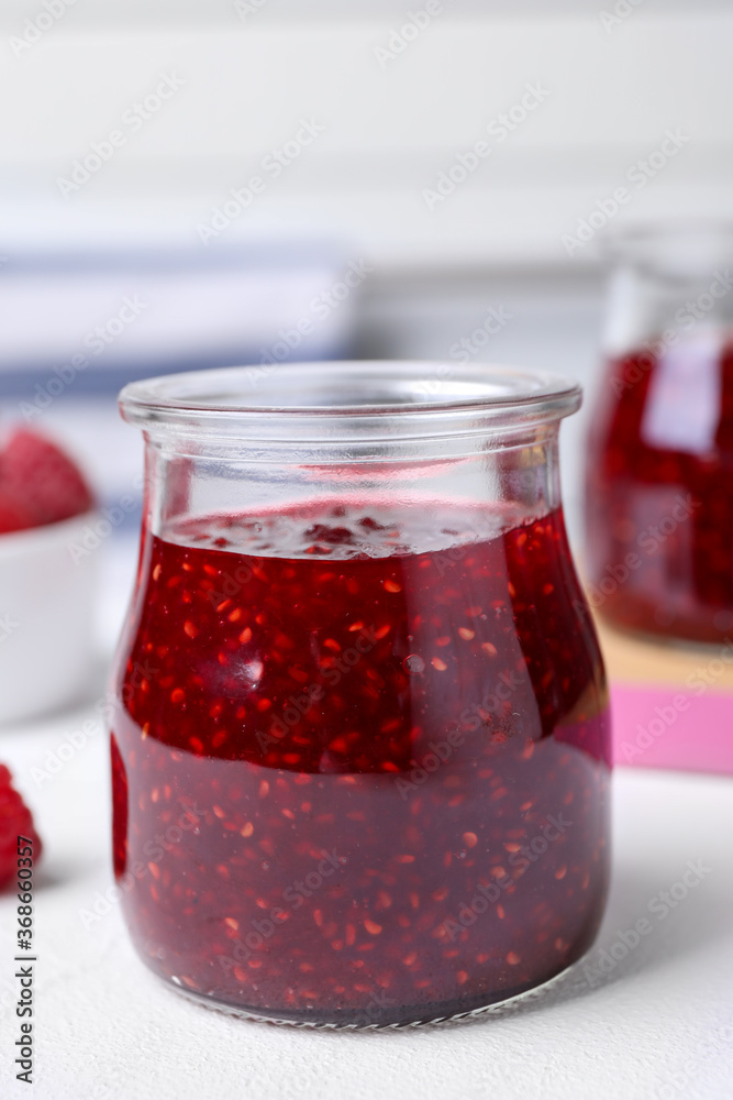 Delicious raspberry jam in jar on white table, closeup Delicious raspberry jam in jar on white table, closeup