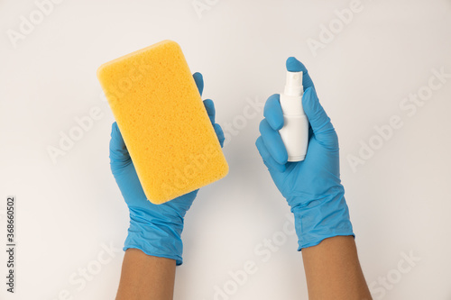 Sponge and spray for cleaning in female hand. Hand in a latex glove isolated on white. A hand in a glove holds a sponge and spray cleaning.