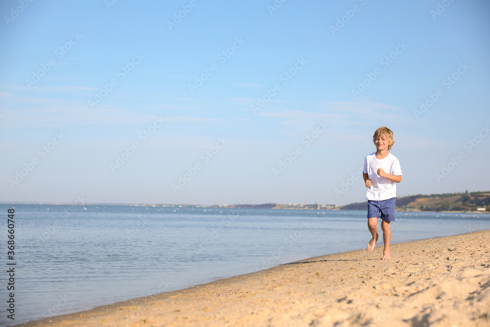Cute little child running at sandy beach on sunny day