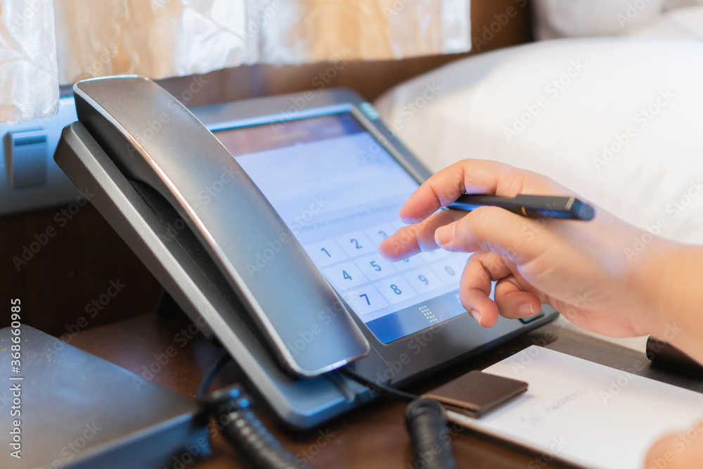 Fototapeta premium Receptionist operator calling phone to communication support, call center to customer service help desk. VOIP in accommodation lobby counter, phone in hotel office
