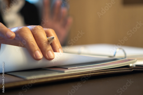 Document report or business management concept: Businessman manager hands holding pen for reading, signing paperwork near payroll salary binder, summary report HR-human resources business in file 