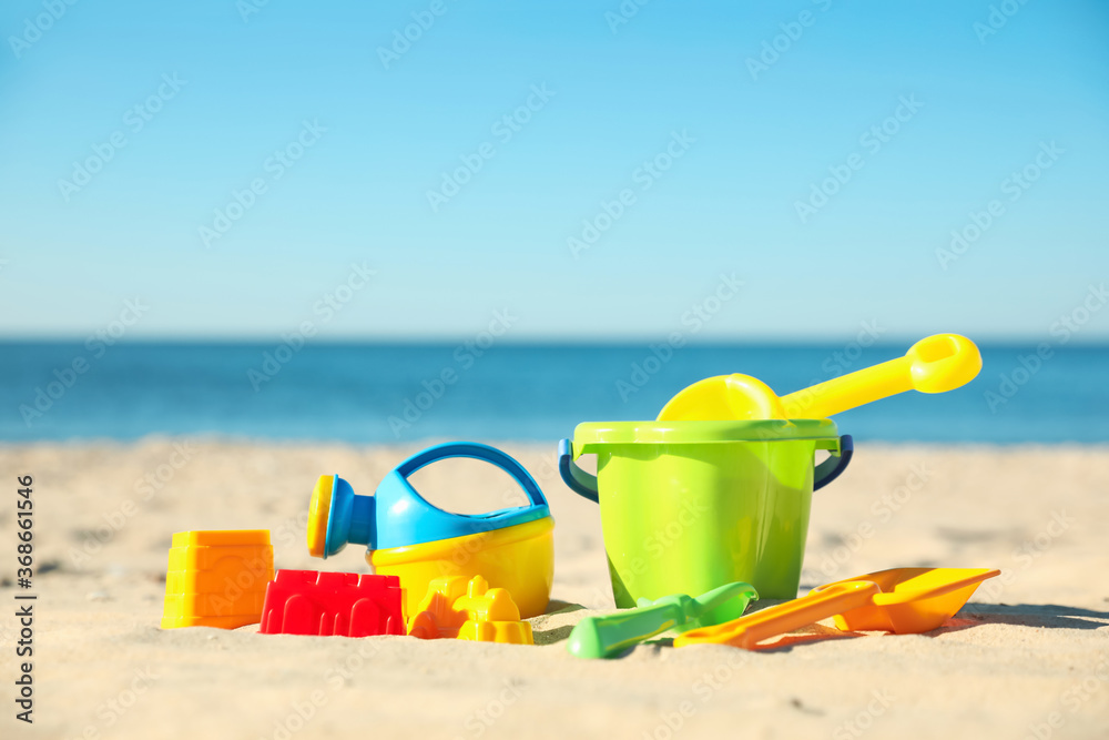 Different child plastic toys on sandy beach. Space for text Different child plastic toys on sandy beach. Space for text