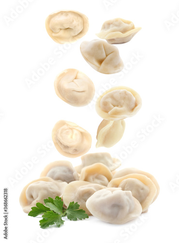 Many tasty dumplings falling on white background