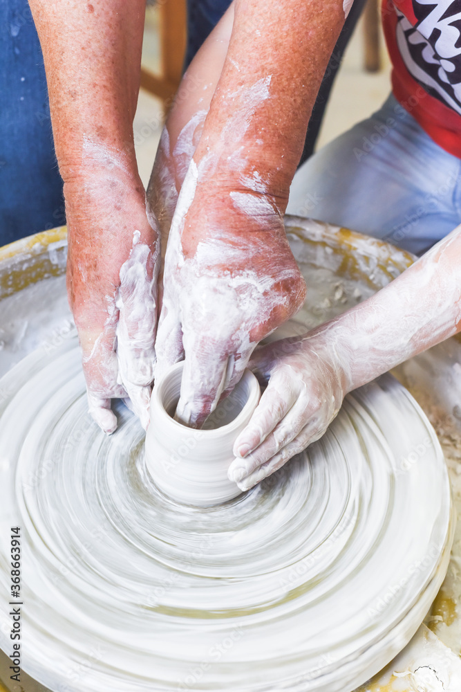 Children learning to make pottery as a hobby with their grandmother in a ceramics workshop