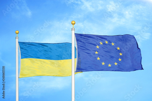 Ukraine and European Union two flags on flagpoles and blue sky