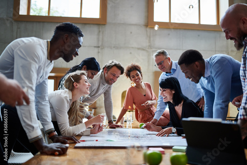 Happy multiethnic professionals discussing while planning strategy at conference table during meeting in creative workplace