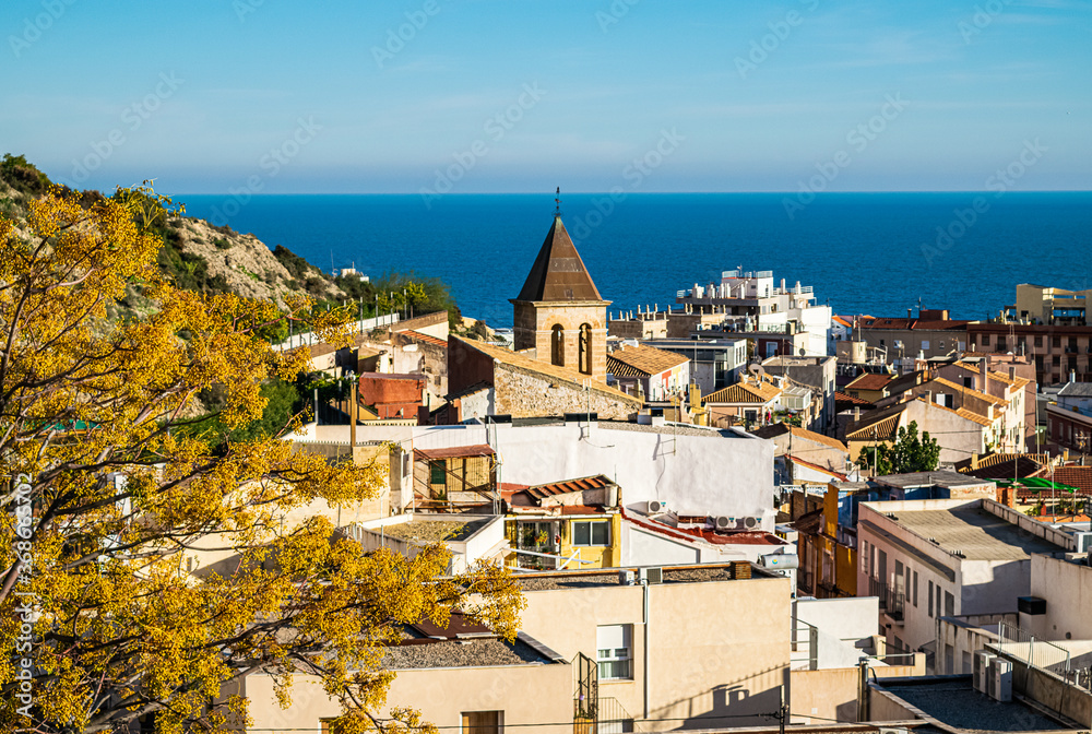 View onto Alicante's historical old town on a sunny day with blue sea in the background.