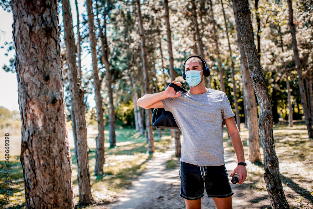 Young man in sportswear with a medical mask on his face going on training. Young man in sportswear with a medical mask on his face going on training.