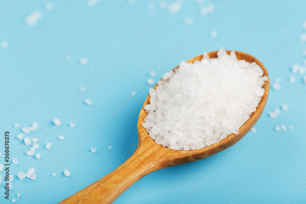 In a wooden spoon, sea salt crystals on a blue background, In a wooden spoon, sea salt crystals on a blue background,