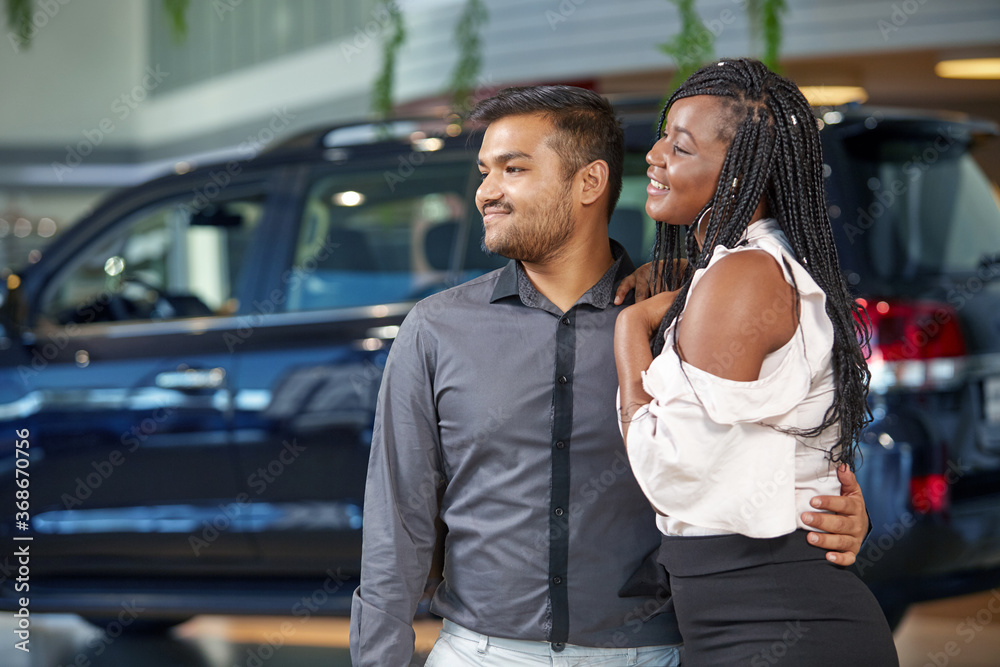 African-American young couple choose a new car at a car dealership, selective focus African-American young couple choose a new car at a car dealership, selective focus