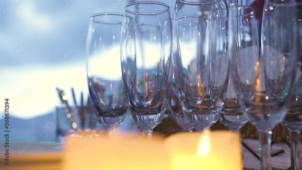 Close up view of empty wine glasses on the table with lighted candles. No people, natural light background. Celebration, wedding or anniversary concept.