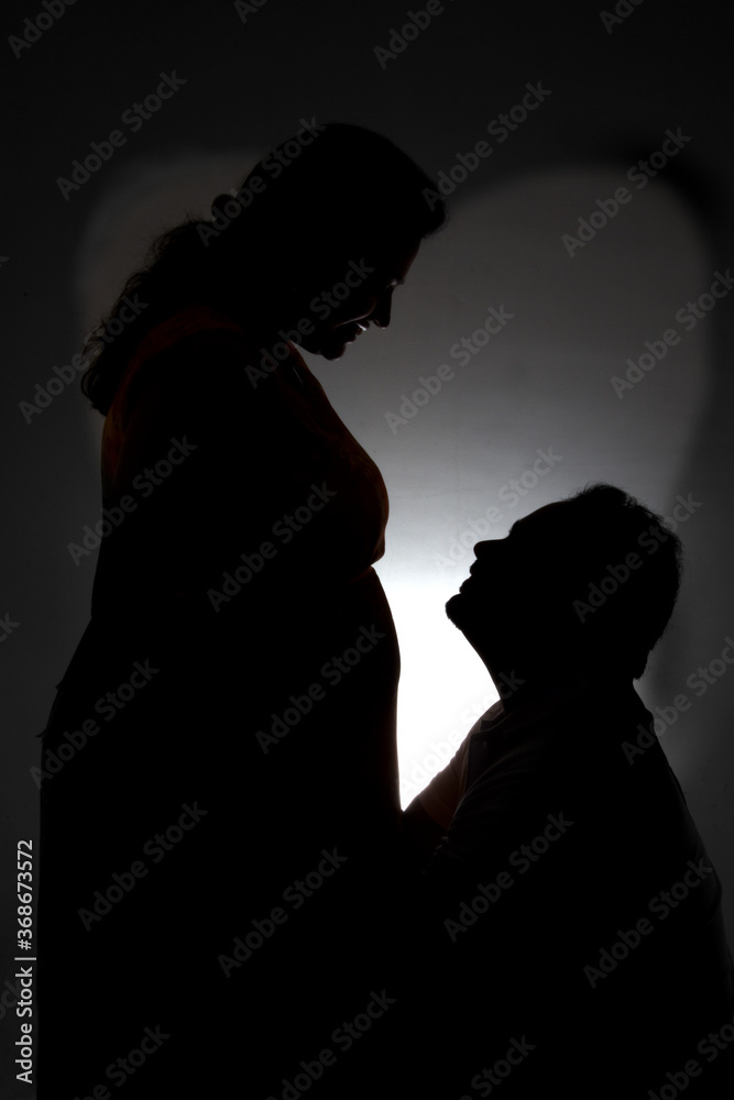 silhouette of mother and father with baby bump