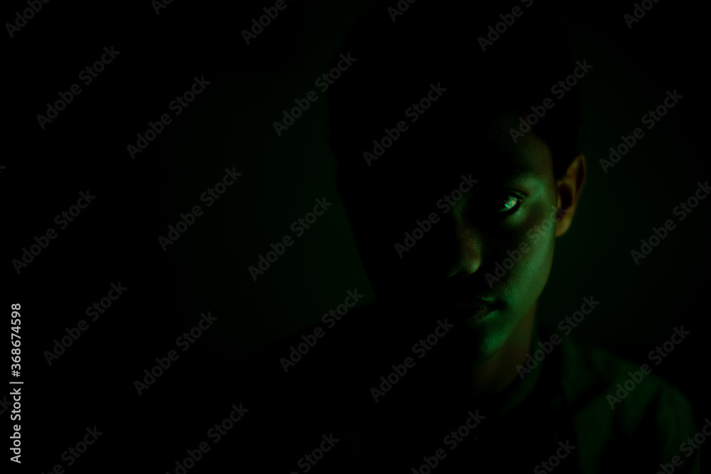 Portrait of teenager staring in dark room Portrait of teenager staring in dark room