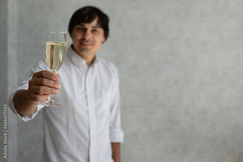 A young guy raises a glass of champagne in honor of the holiday. Place for text. A young guy raises a glass of champagne in honor of the holiday. Place for text.