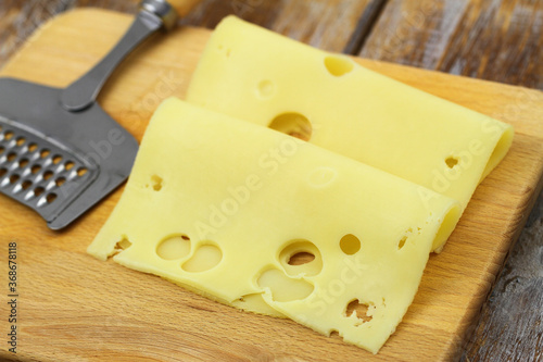 Slices of tasty Swiss cheese on wooden board

