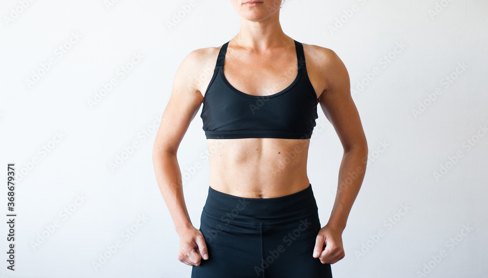 Beautiful sporty woman in black leggings posing on grey background. Photo of girl with slim toned body. Beauty and body care concept Beautiful sporty woman in black leggings posing on grey background. Photo of girl with slim toned body. Beauty and body care concept