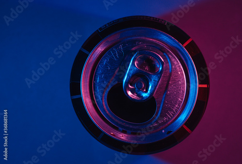 Top down view of open soda metal can lit by red and blue light.