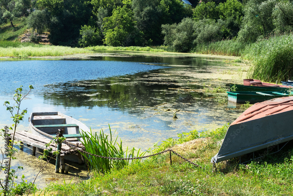 An old abandoned boat on the pond. Beautiful scenic landscape on the Tyasmin river, Kamyanka, Ukraine. Travel by Ukraine. An old abandoned boat on the pond. Beautiful scenic landscape on the Tyasmin river, Kamyanka, Ukraine. Travel by Ukraine.