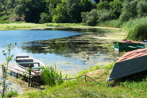 An old abandoned boat on the pond. Beautiful scenic landscape on the Tyasmin river, Kamyanka, Ukraine. Travel by Ukraine.