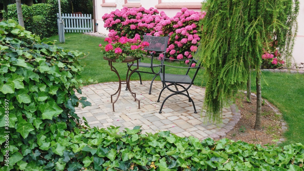 Tisch mit Blumen und sehr grünem Garten