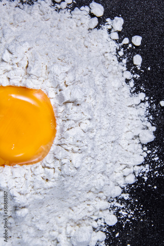 Broken eggs and flour for baking cakes with black background