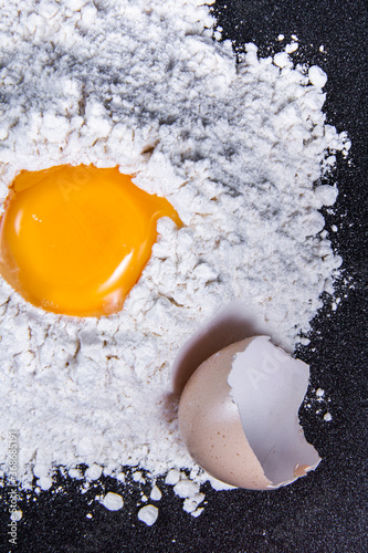 Broken eggs and flour for baking cakes with black background