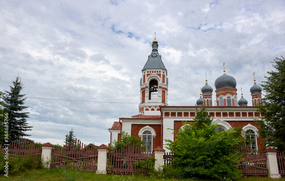Beautiful bell tower of an Orthodox Church against a cloudy blue sky.
