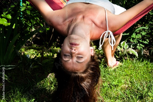 woman enjoy relaxing in a hammock. girl sleep in hammock. summer rest. sexy girl lay upside down with long hanging hair. concept of healthy skin and hair