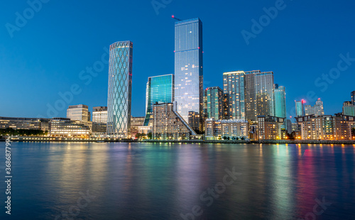 Financial district of London city Canary Wharf reflected on the Thames river at blue hour in England