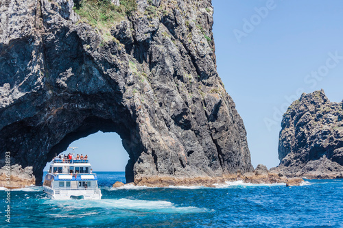 Tour boat entering The Hole in the Rock in Bay of Islands, New Zealand