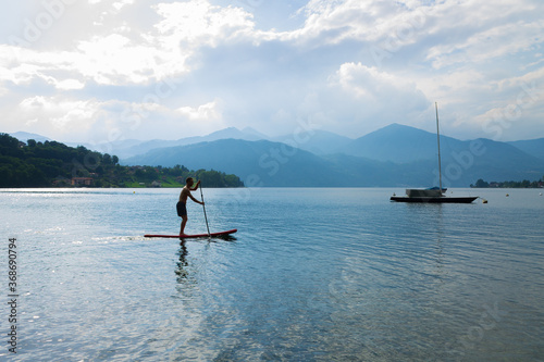 A young man standing up paddle board in Lake Orta, Italy