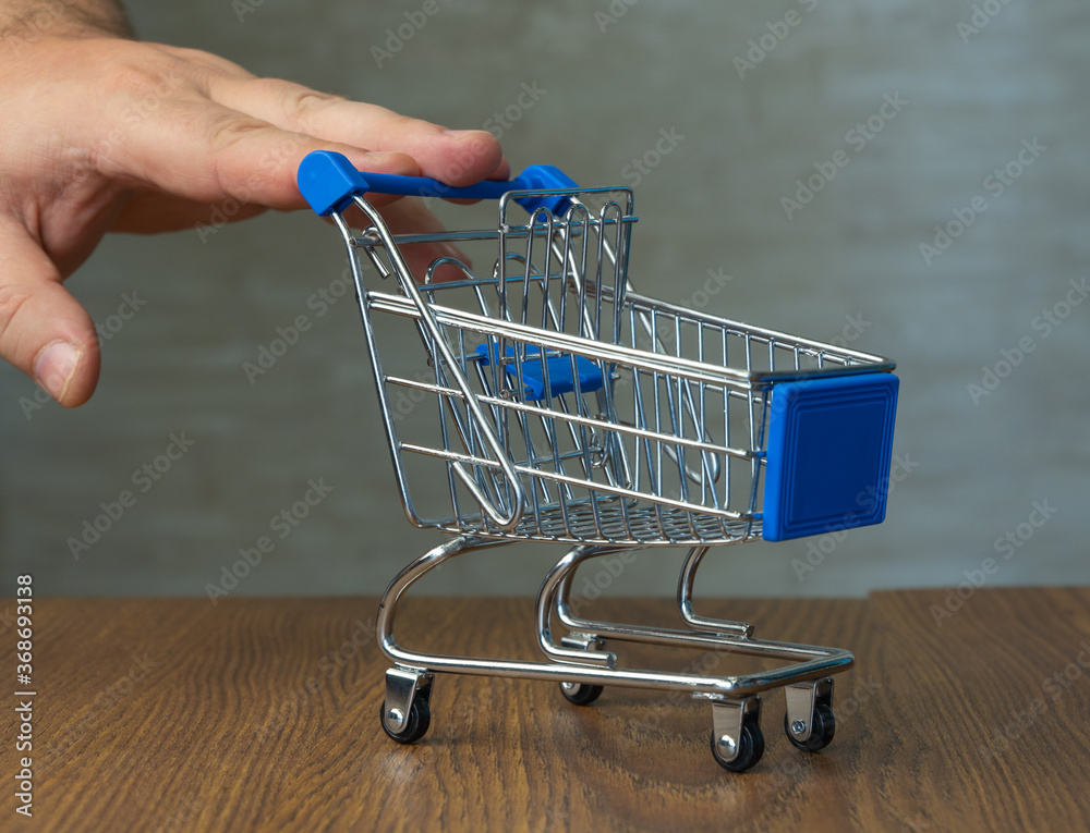 shopping cart. in the background, a man orders a product on a laptop. selective focus. online shopping.